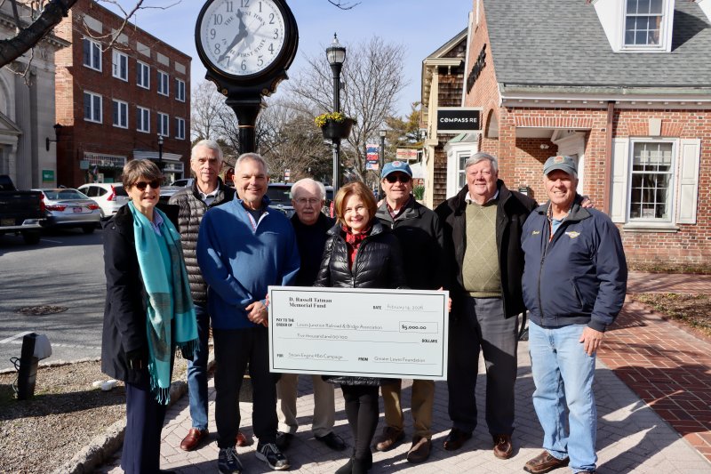 Cathy Tatman holds a large check with a $5,000 donation to the Lewes Junction Railroad and Bridge Association Jan. 23. The donation is the first to the Greater Lewes Foundation’s newly launched community campaign to “Bring #60 for 250.” No. 60 is LJRBA’s 1913 locomotive, which is due to arrive in Stango Park in late spring. Shown are (l-r) Andrea Brock, LJRBA; Gerry Kaplan, LJRBA; Robert Kennedy, LJRBA; Joe Stewart, Greater Lewes Foundation; Cathy Tatman, LJRBA; Randy Voith, LJRBA; Mike Rawl, Greater Lewes Foundation; and David Ludlow, LJRBA. BILL SHULL PHOTO